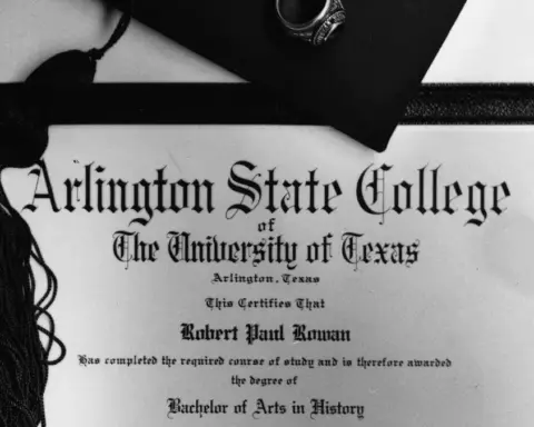 A formal university graduation diploma rolled with a ribbon alongside an academic graduation cap.
