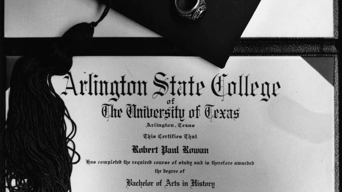 A formal university graduation diploma rolled with a ribbon alongside an academic graduation cap.
