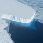 Blue ice calving front of Thwaites Glacier meeting the Southern Ocean, photographed from a NASA research aircraft