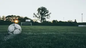 A black-and-white football resting on a grass field before play.