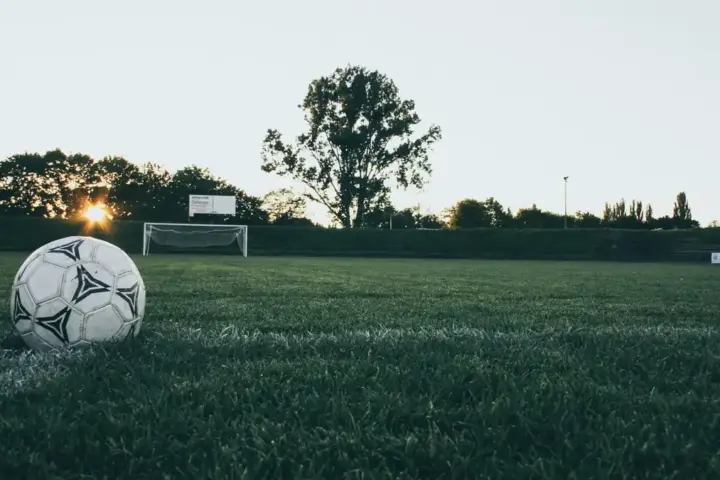 A black-and-white football resting on a grass field before play.