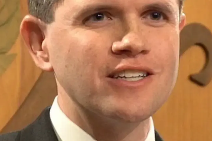 James Talarico speaking into microphones during an official legislative press conference at the Texas State Capitol.