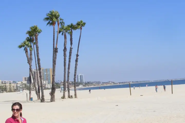 Coastal ocean waters, sandy beach, and urban boardwalk fortifications along the Long Beach shoreline in Southern California.