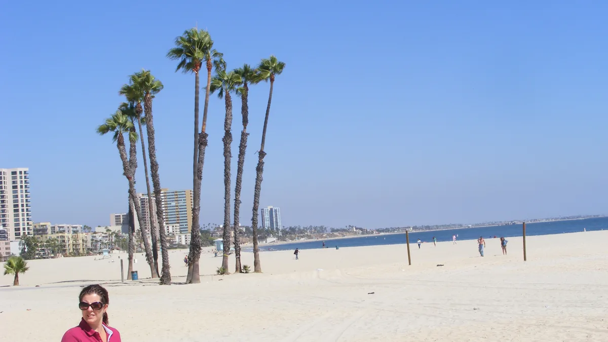 Coastal ocean waters, sandy beach, and urban boardwalk fortifications along the Long Beach shoreline in Southern California.