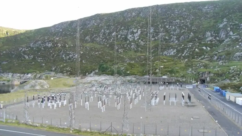 Pumped-storage hydroelectric power station switchyard set against a mountainous reservoir landscape