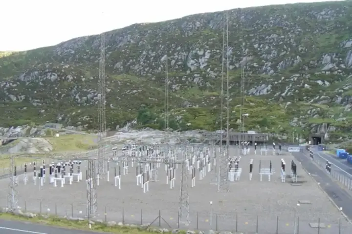 Pumped-storage hydroelectric power station switchyard set against a mountainous reservoir landscape