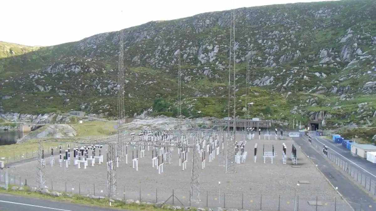 Pumped-storage hydroelectric power station switchyard set against a mountainous reservoir landscape