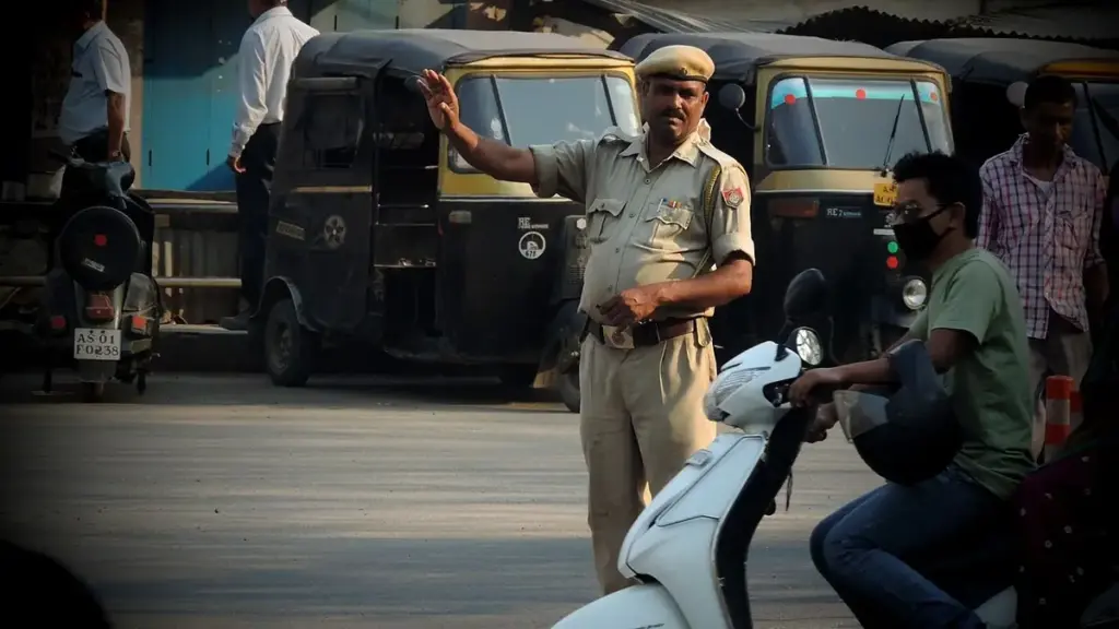 Traffic officer managing vehicles at a busy Indian road intersection.
