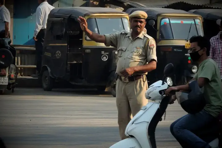 Traffic officer managing vehicles at a busy Indian road intersection.