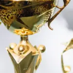 Close view of a polished gold trophy with a smaller trophy blurred in the background.