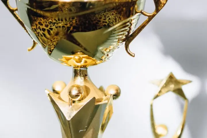 Close view of a polished gold trophy with a smaller trophy blurred in the background.