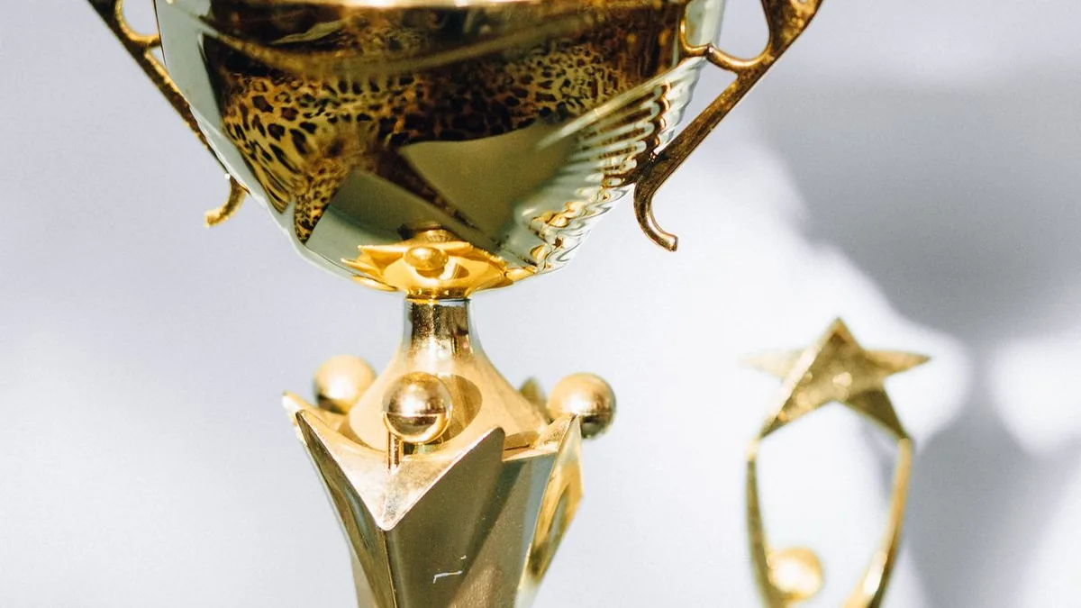 Close view of a polished gold trophy with a smaller trophy blurred in the background.