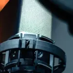 Close-up of a professional studio microphone and pop filter used for voice recording.