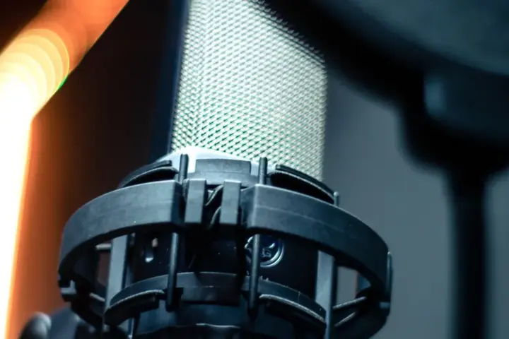Close-up of a professional studio microphone and pop filter used for voice recording.