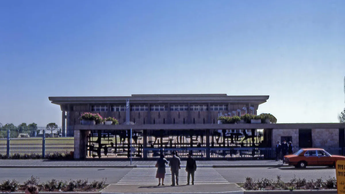 Front view of the stone Knesset parliament building and surrounding plaza in Jerusalem.