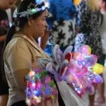 Brightly lit colourful light-up toys and accessories on display at a bustling night market stall.