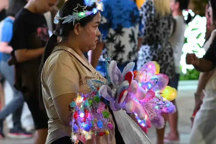 Brightly lit colourful light-up toys and accessories on display at a bustling night market stall.