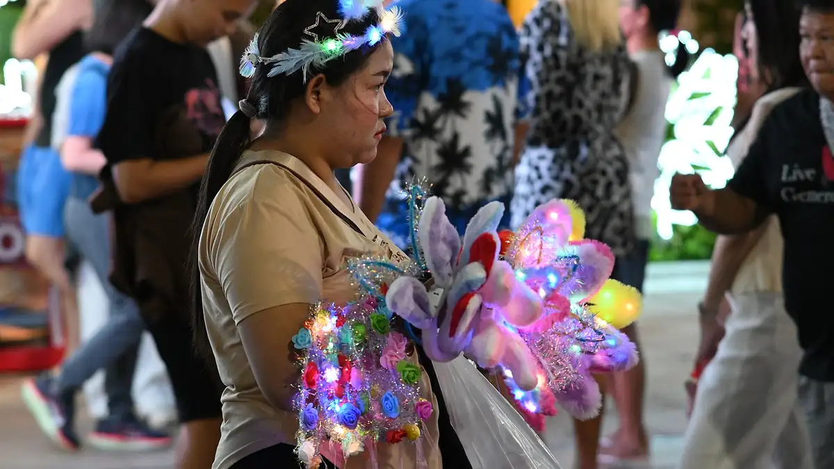Brightly lit colourful light-up toys and accessories on display at a bustling night market stall.