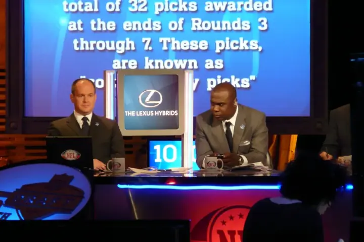 Hall of Fame running back Marshall Faulk seated at a broadcast desk.