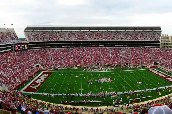Panoramic view of the full grandstands, field, and upper decks of Bryant-Denny Stadium during a collegiate athletic event in Alabama.