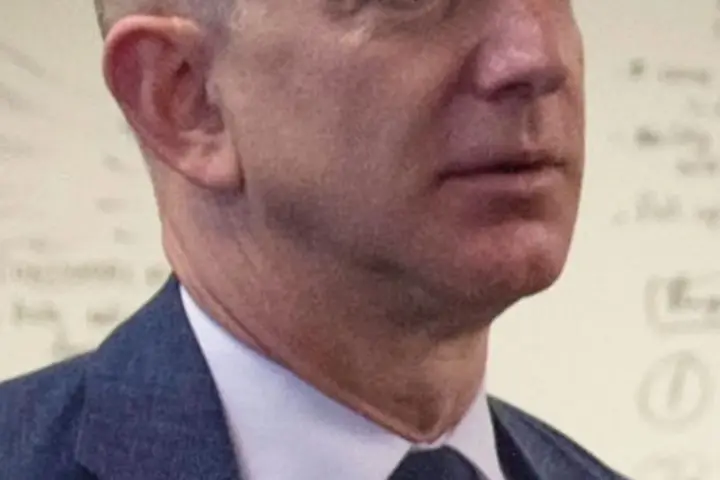 Formal portrait photograph of Amazon founder Jeff Bezos speaking during an official executive gathering.