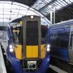 ScotRail modern electric passenger train standing at an urban railway station platform