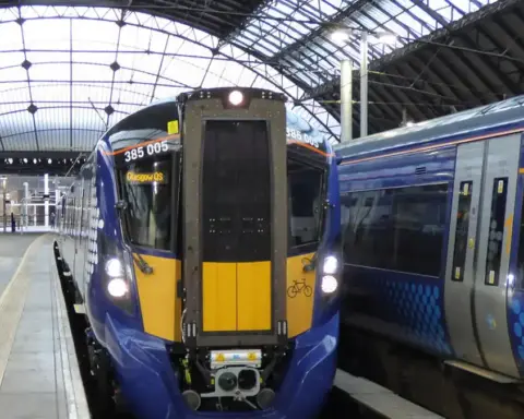 ScotRail modern electric passenger train standing at an urban railway station platform