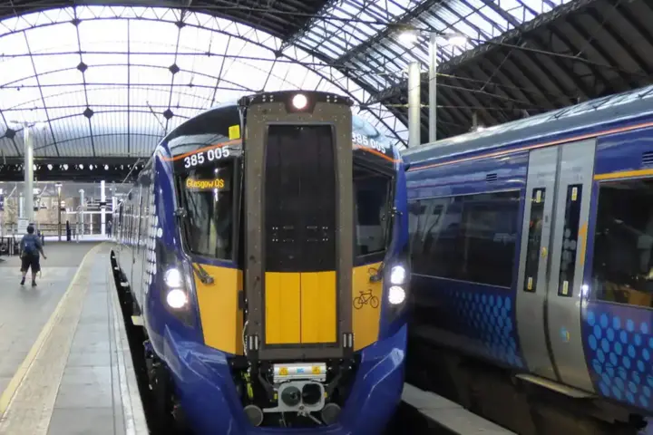 ScotRail modern electric passenger train standing at an urban railway station platform