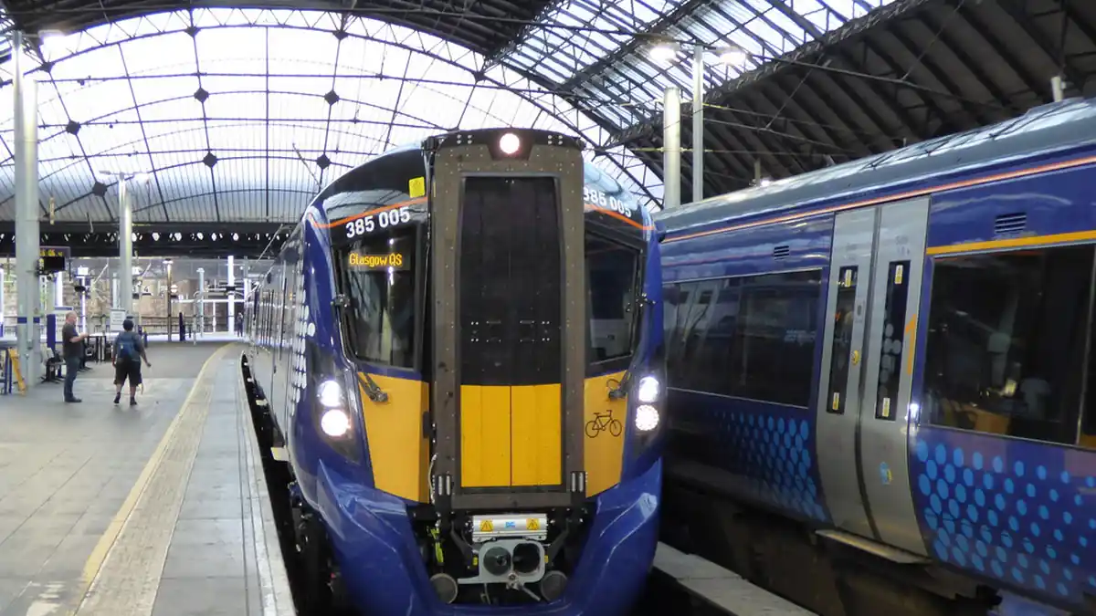 ScotRail modern electric passenger train standing at an urban railway station platform