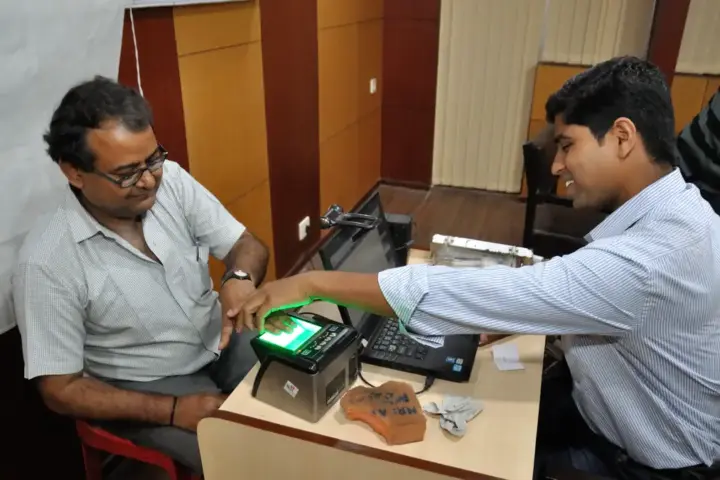 Person placing fingers on a biometric scanner during identity enrollment