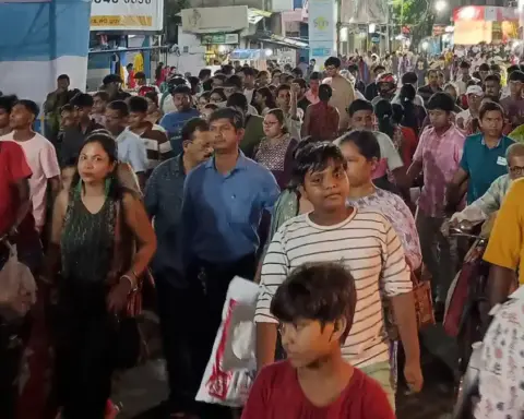Dense crowd of devotees moving through a narrow Kolkata street during a Durga Puja festival night