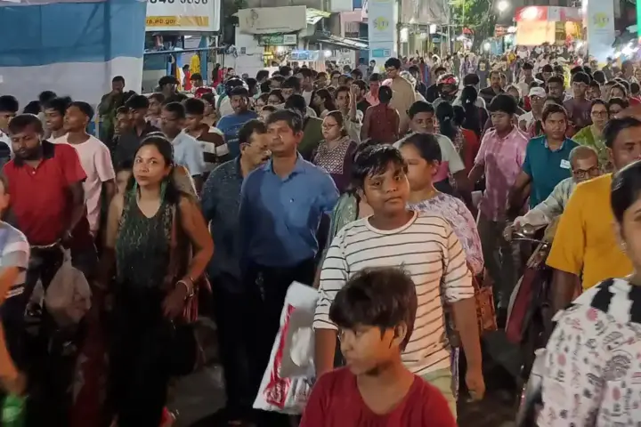 Dense crowd of devotees moving through a narrow Kolkata street during a Durga Puja festival night