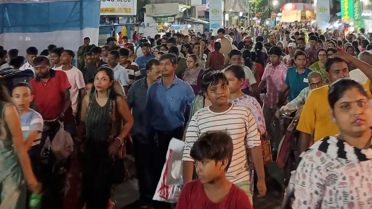 Dense crowd of devotees moving through a narrow Kolkata street during a Durga Puja festival night