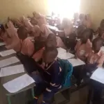 Students writing examinations in a classroom setting.