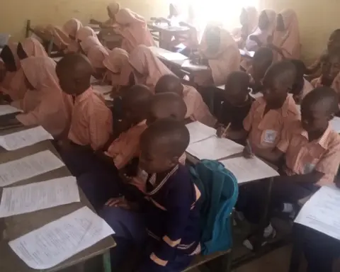 Students writing examinations in a classroom setting.