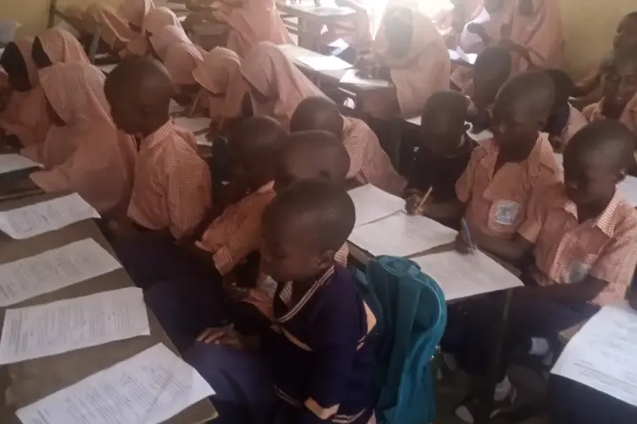 Students writing examinations in a classroom setting.
