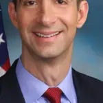 Official studio portrait of U.S. Senator Tom Cotton in a dark suit with tie and American flag lapel pin
