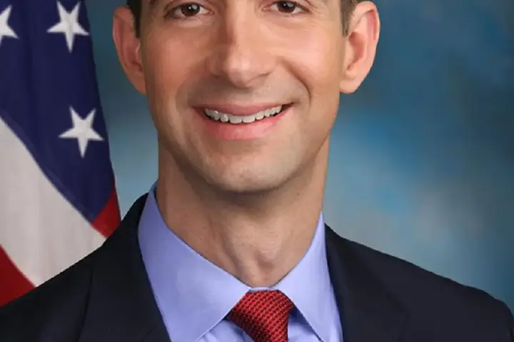 Official studio portrait of U.S. Senator Tom Cotton in a dark suit with tie and American flag lapel pin
