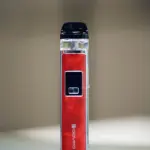 A red and silver vape device on a plain white surface