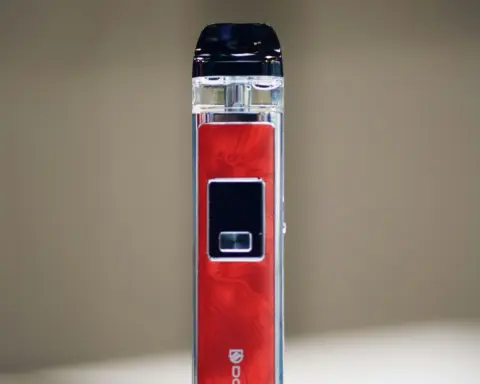 A red and silver vape device on a plain white surface