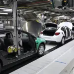 Automotive assembly line with workers installing car components in a factory setting
