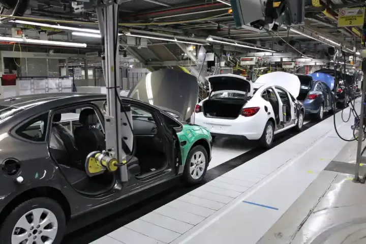 Automotive assembly line with workers installing car components in a factory setting