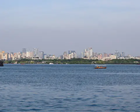 West Lake and Hangzhou city skyline with modern buildings reflected in the lake.