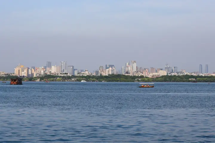 West Lake and Hangzhou city skyline with modern buildings reflected in the lake.