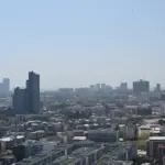 Flat rooftops and high-rise buildings under a clear, hazy, sunlit sky.