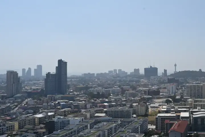 Flat rooftops and high-rise buildings under a clear, hazy, sunlit sky.